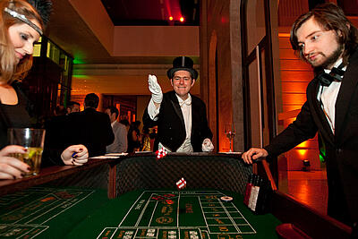 Man in top hat throws the dice at the craps table at a 20s event