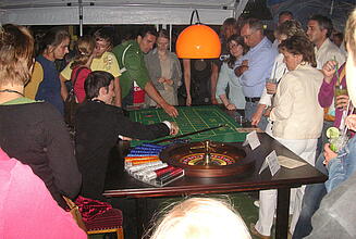 Company summer party with roulette table Guests at a company summer party play roulette in a pavilion.