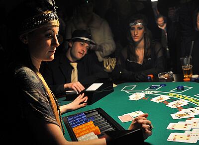 Croupier in 20s outfit plays blackjack with the dressed-up guests.